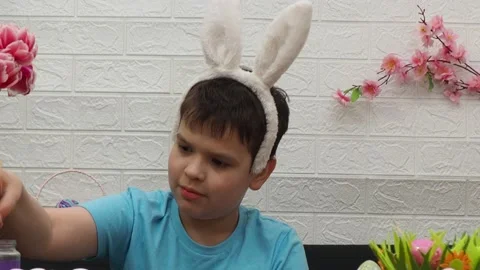 Easter holiday.  bunny ears. A boy  paints an Easter egg. Preparing for Easter 動画素材 173758552