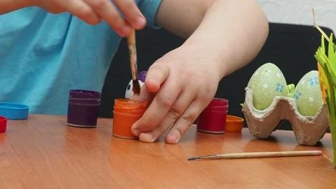 Easter holiday.  bunny ears. A boy  paints an Easter egg. Preparing for Easter 動画素材 173761441