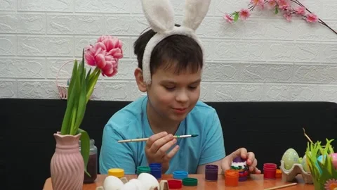Easter holiday.  bunny ears. A boy  paints an Easter egg. Preparing for Easter 動画素材 173765797