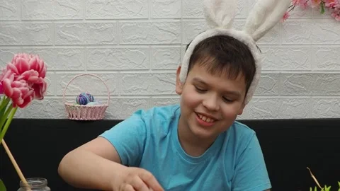 Easter holiday.  bunny ears. A boy  paints an Easter egg. Preparing for Easter 動画素材 173767575