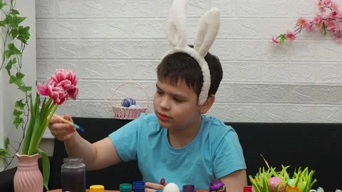 Easter holiday.  bunny ears. A boy  paints an Easter egg. Preparing for Easter 動画素材 173768600