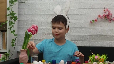 Easter holiday.  bunny ears. A boy  paints an Easter egg. Preparing for Easter 動画素材 173772235