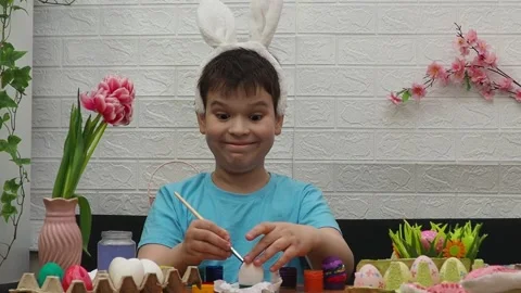 Easter holiday.  bunny ears. A boy  paints an Easter egg. Preparing for Easter 動画素材 173774357