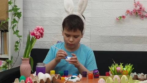 Easter holiday.  bunny ears. A boy  paints an Easter egg. Preparing for Easter 動画素材 173777643