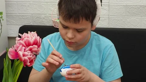 Easter holiday.  bunny ears. A boy  paints an Easter egg. Preparing for Easter 動画素材 173777669