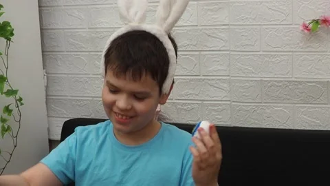 Easter holiday.  bunny ears. A boy  paints an Easter egg. Preparing for Easter 動画素材 173779401