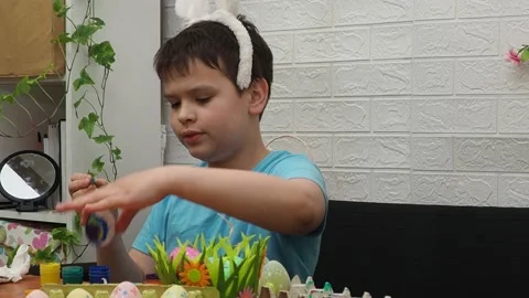 Easter holiday.  bunny ears. A boy  paints an Easter egg. Preparing for Easter 動画素材 173780583