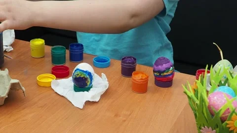 Easter holiday.  bunny ears. A boy  paints an Easter egg. Preparing for Easter 動画素材 173780933