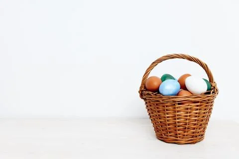 Easter holiday with colored eggs in a basket light background Stock Photos
