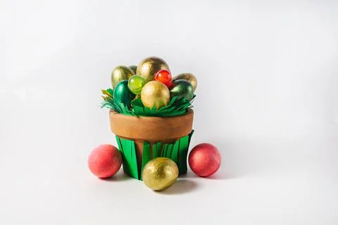 Easter holiday concept. Pot with colored eggs and sweets on a white backgroun Stock Photos