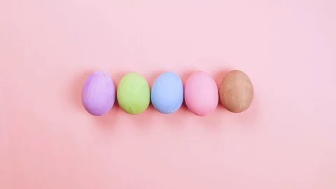 Easter holiday concept stop motion. Egg appear in row, pink background, top view Video stock 126720321