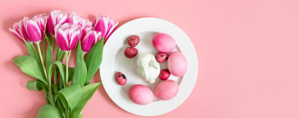 Easter holiday pink table setting with eggs, rabbit and a bouquet of tulips.  Stock Photos