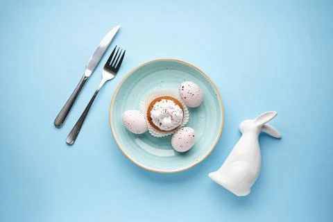 Easter holiday table setting and plates with colorful eggson a blue backgroun Stock Photos