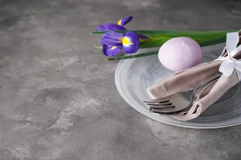 Easter holiday table setting and plates with colorful eggs on a grey backgrou Stock Photos