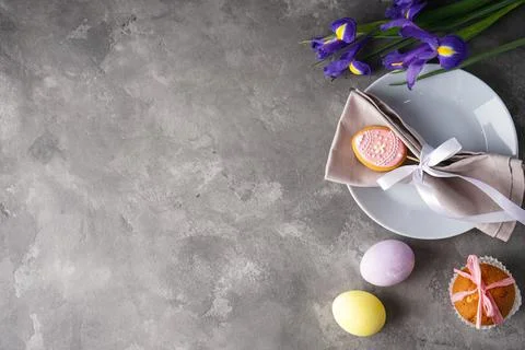 Easter holiday table setting and plates with colorful eggs on a grey backgrou Stock Photos