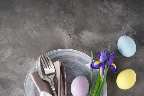 Easter holiday table setting and plates with colorful eggs on a grey backgrou Stock Photos