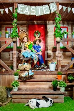Easter holidays. Happy children are posing on the porch of a village house. E Stock Photos
