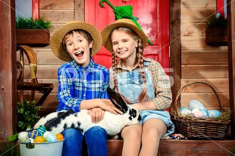 Easter holidays. Happy children are posing on the porch of a village house. E Stock Photos