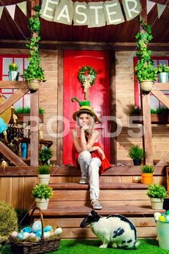 Easter holidays. Happy girl is posing on the porch of a village house and rab Stock Photos