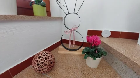 Easter interior decoration with metal rabbit and flower pot on stairs Stock Footage 333643240