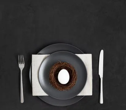 Easter minimal table setting with an egg nest on a black background. Stock Photos