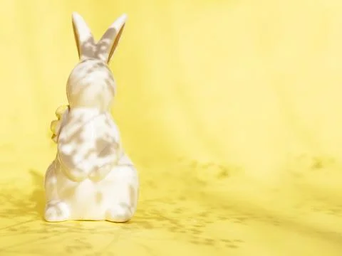 Easter minimalistic background with a ceramic rabbit and a shadow of flowers on Stock Photos