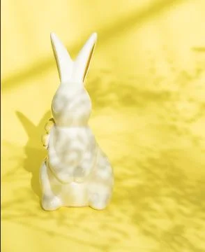 Easter minimalistic background with a ceramic rabbit and a shadow of flowers on Foto stock