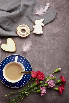 Easter minimalistic coffee time. Glazed cookies, coffee cup, feathers, aster Stock Photos