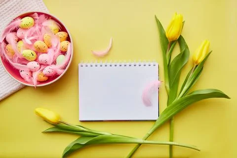 Easter mock up notepad. Pink bright bowl with colorful eggs, pink feathers and Foto stock