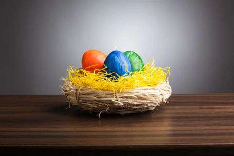 Easter nest with colored eggs on table, gray background Stock Photos