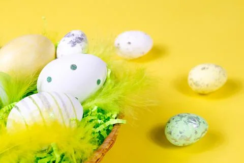 Easter nest with eggs and feathers on a yellow background close-up. Minimal Stock Photos