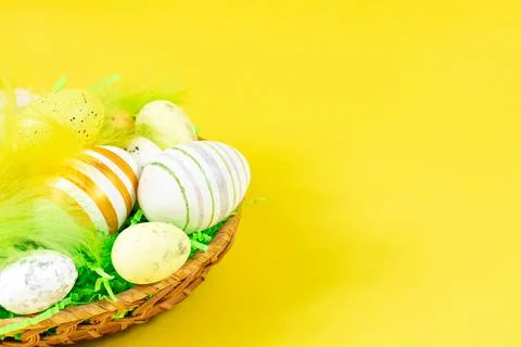 Easter nest with eggs and feathers on a yellow background close-up. Place for an Stock Photos
