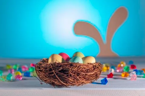 Easter nest, hidden eggs by a hare. Egg hunt. Easter Bunny on a blurry backgr Stock Photos