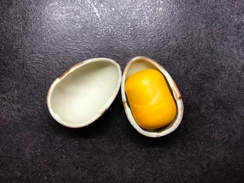 Easter open chocolate kinder egg with a yellow core on a black table Stock Photos