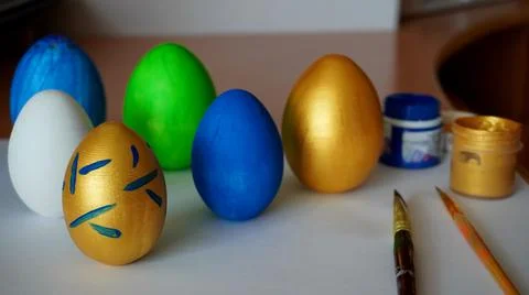 Easter with painted chicken eggs with paint brushes in blue, gold, green colors  Foto stock