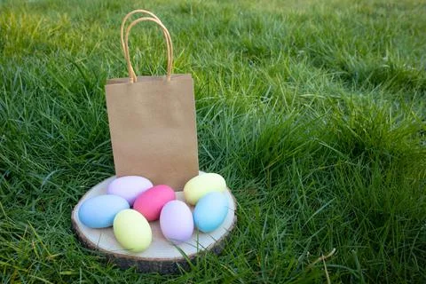 Easter a paper bag and multi-colored eggs on a wooden stand, stand on the grass Stock Photos