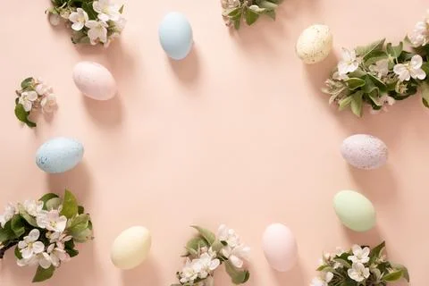 Easter pastel eggs and spring flowers border on peach background Stock Photos