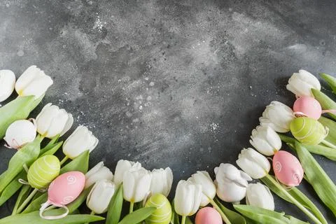 Easter pattern. Border of white tulips, eggs, nest on vintage gray. Stock Photos