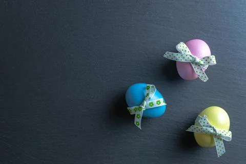 Easter pattern. Colorful egg with tape ribbon on dark rough stone background  Stock Photos