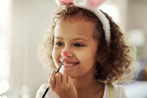 Easter is the perfect time to be a bunny. a little girl painting her face to Stock Photos