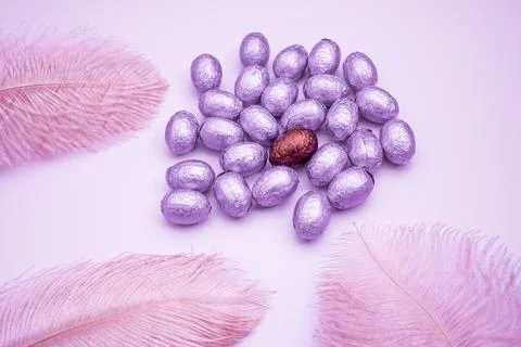 Easter pink background with chocolate easter eggs wrapped in purple colored f Stock Photos
