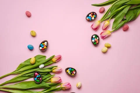 Easter pink background with chocolate rabbit, easter eggs and tulips. Stock Photos