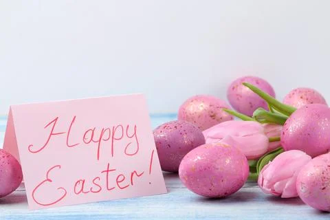 Easter. Pink easter eggs and flowers tulips on a blue wooden table. Happy eas Stock Photos