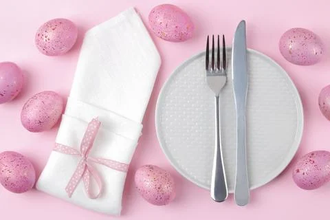 Easter. Pink Easter eggs and plate, knife and fork on a trendy pink backgroun Stock Photos