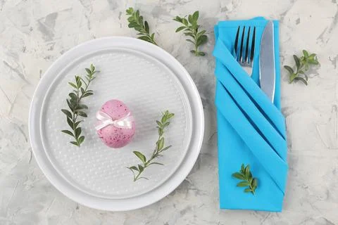 Easter. Pink Easter eggs and a knife with a fork and a plate on a light concr Stock Photos