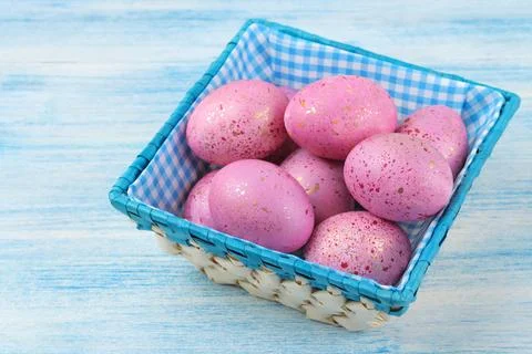 Easter. Pink easter eggs in a basket on a blue wooden table. Happy easter. ho Stock Photos
