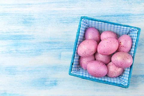 Easter. Pink easter eggs in a basket on a blue wooden table. Happy easter. ho Stock Photos