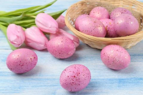 Easter. Pink Easter eggs in a basket and flowers tulips on a blue wooden tabl Stock Photos