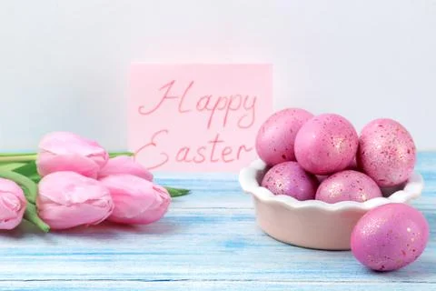 Easter. Pink Easter eggs in a bowl and flowers tulips on a blue wooden table. Stock Photos