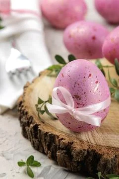 Easter. Pink Easter eggs on a wooden stand on a light concrete background. Ha Stock Photos